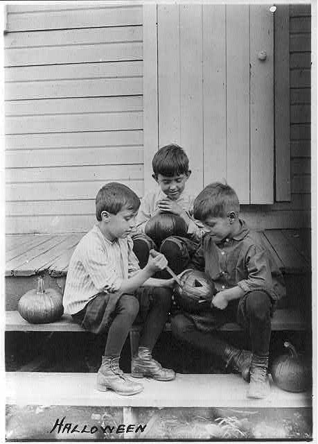 Three boys carving pumpkins around 1917.